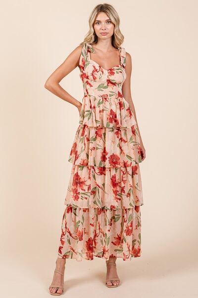 Woman wearing a blush pink floral print tiered maxi dress with tie shoulder straps