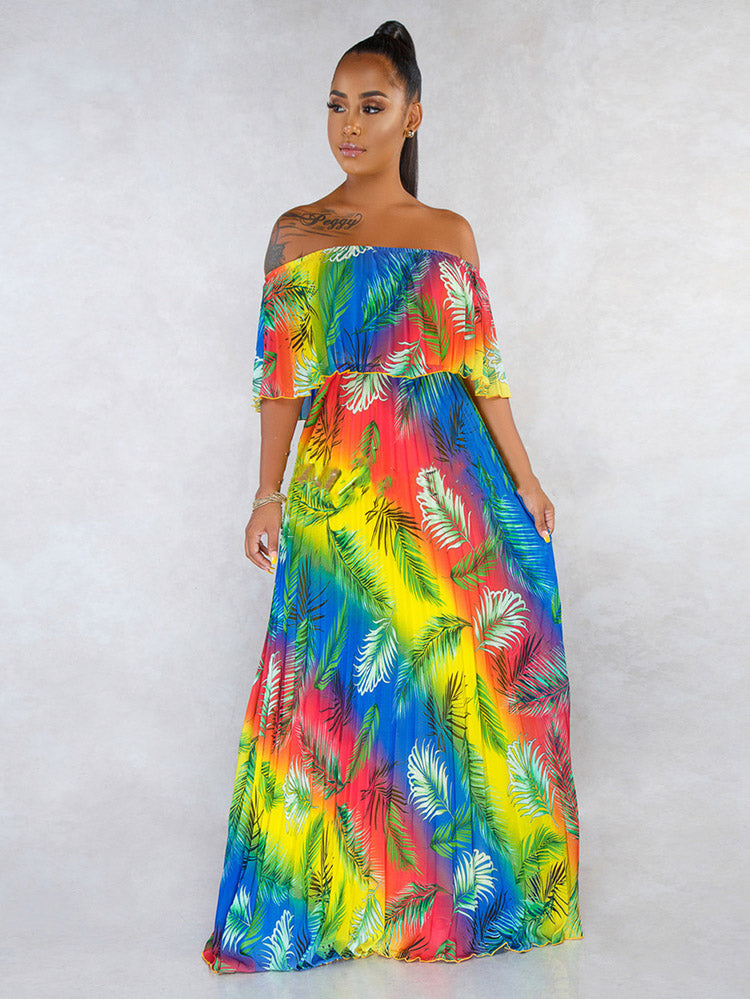 Woman wearing a rainbow gradient off-the-shoulder maxi dress with a tropical leaf print, posing against a neutral background.