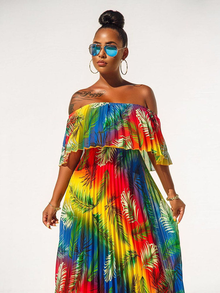 Close-up of a woman wearing a rainbow gradient off-the-shoulder maxi dress with a tropical leaf print and sunglasses.
