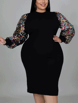 Three-quarter view of a woman in a black sheath dress with shimmering sequin sleeves and a mock neckline.