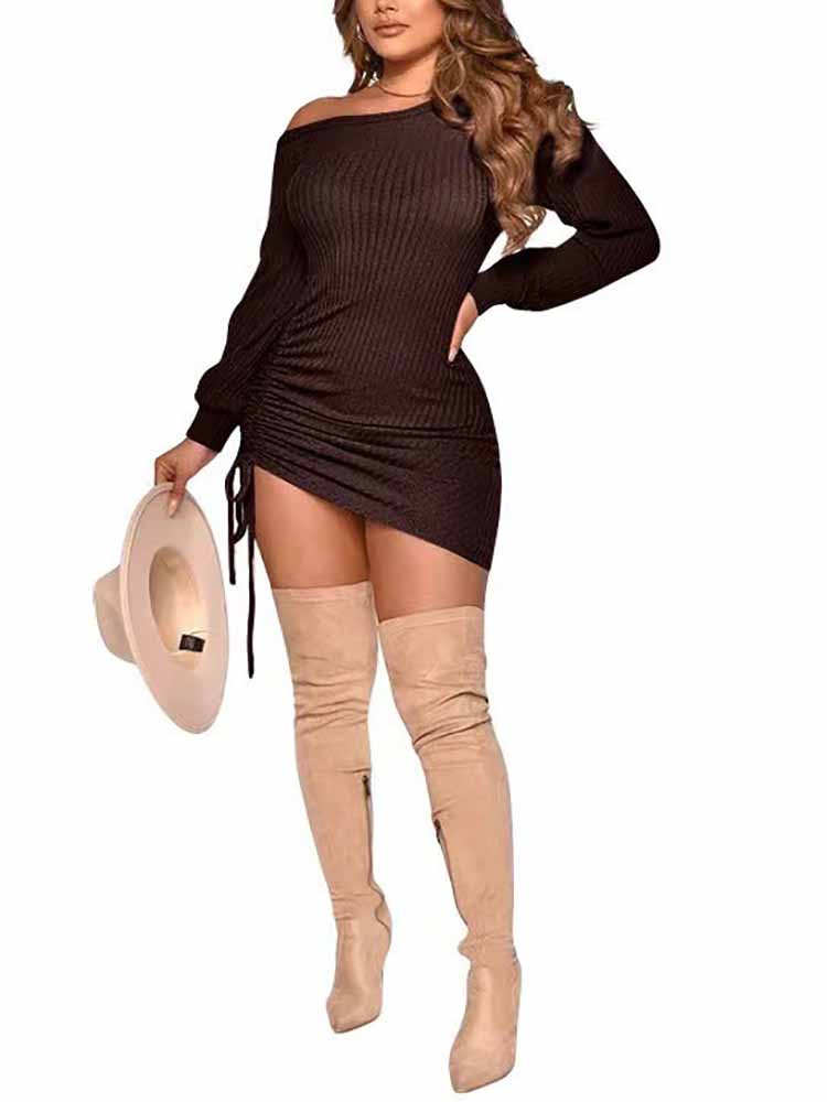 Woman in a brown ribbed knit mini dress with bishop sleeves and a ruched side detail, holding a hat.