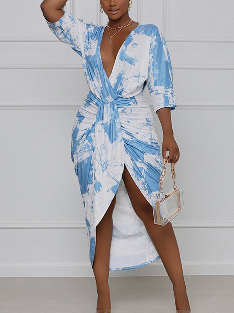 Woman wearing a blue and white tie-dye print wrap dress with a v-neck and high slit.