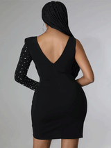 Back view of a woman wearing a black sheath dress with a V-neck and a long embellished sleeve.