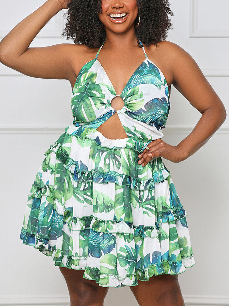 Woman with curly hair wearing a green and white leaf print halter dress with cut-out waist and tiered skirt