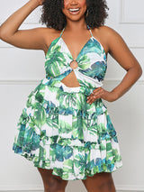Woman with curly hair wearing a green and white leaf print halter dress with cut-out waist and tiered skirt