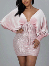 Woman wearing a pink velvet and sequin mini dress with dolman sleeves