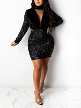 Woman wearing a black sequined mini dress with velvet bodice and long sleeves, front view.