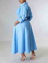Back view of a woman in a light blue A-line shirt dress with pockets.