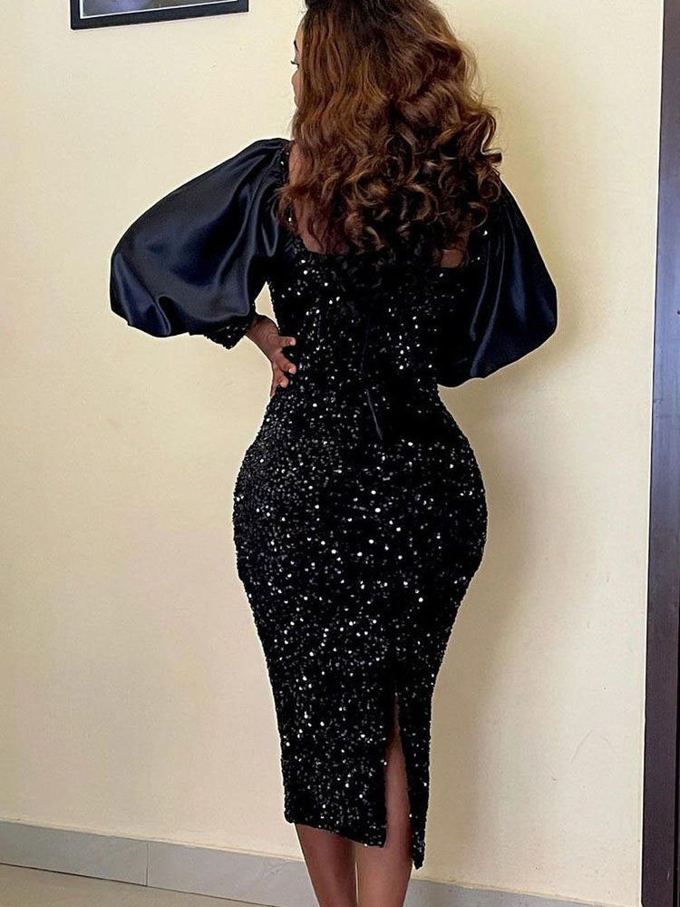 Back view of a woman in a black sequined midi dress with long puff sleeves and a square neckline, showing the slit detail.