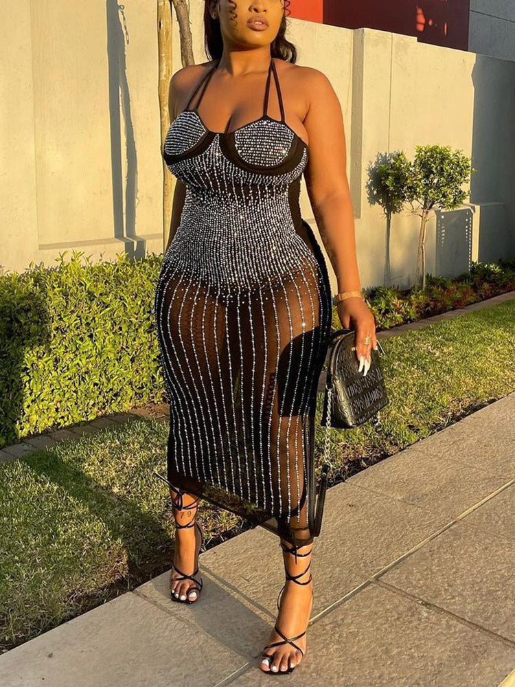 woman in a black embellished sheer midi dress with halter neckline and strappy heels