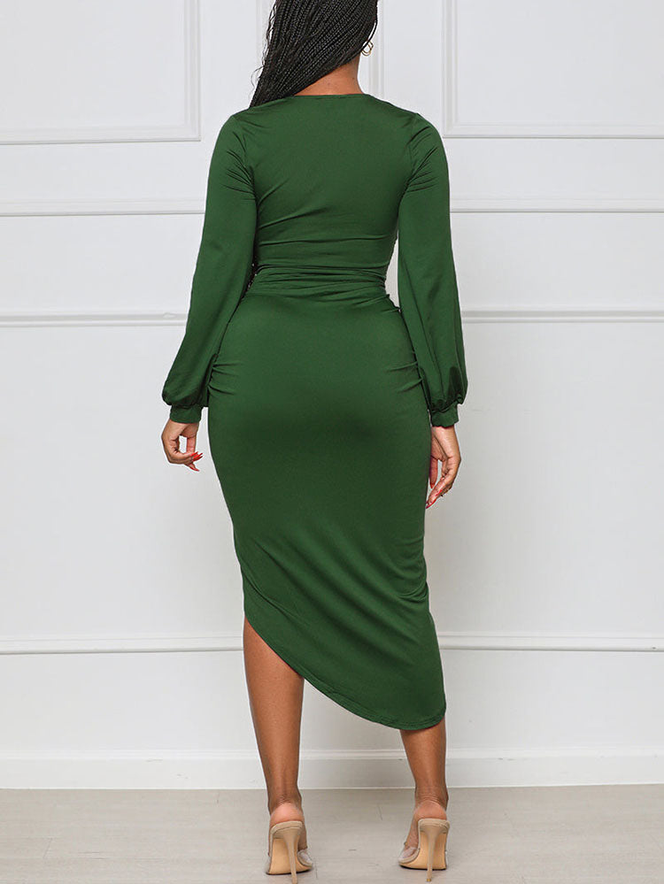 Back view of a woman in a green long-sleeve ruched V-neck dress with an asymmetrical hem and high slit.