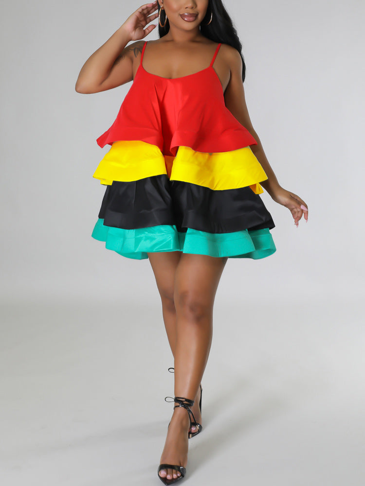 Woman wearing a red, yellow, black, and teal tiered mini dress with spaghetti straps and black ankle-strap heels.