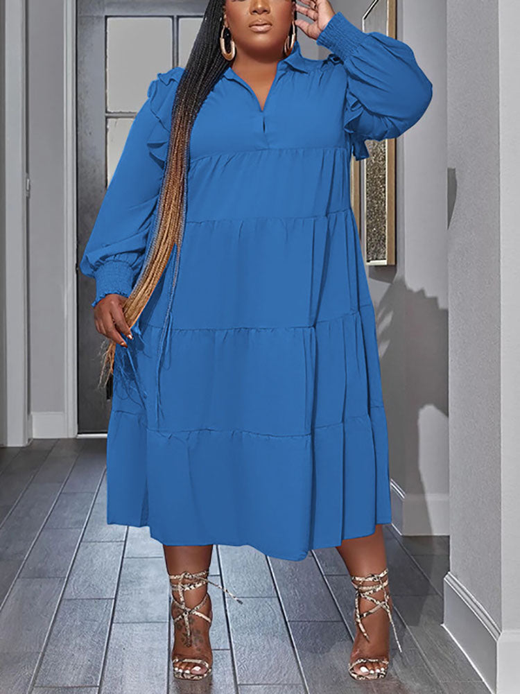 Plus-size model wearing a royal blue tiered midi dress with voluminous sleeves and long braided hair.