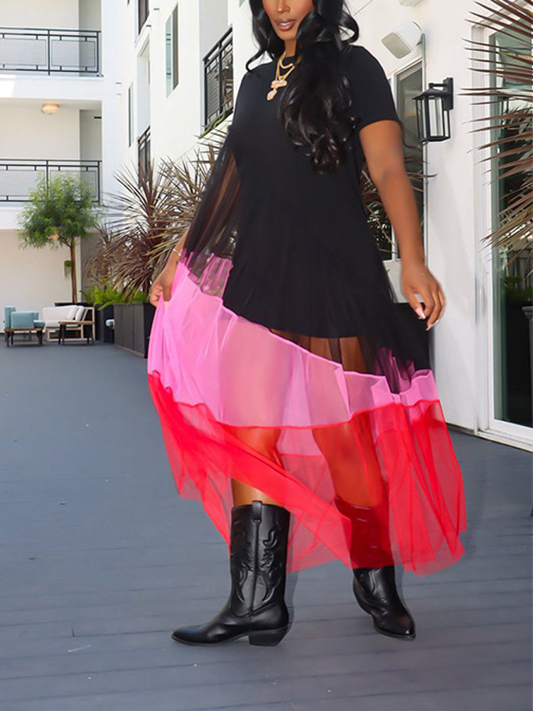 Woman in a black short-sleeved dress with a flowing, color-blocked mesh skirt in pink and red, showcasing the sheer layers.