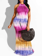 Woman wearing a tie-dye halter maxi dress in magenta, purple, and yellow.