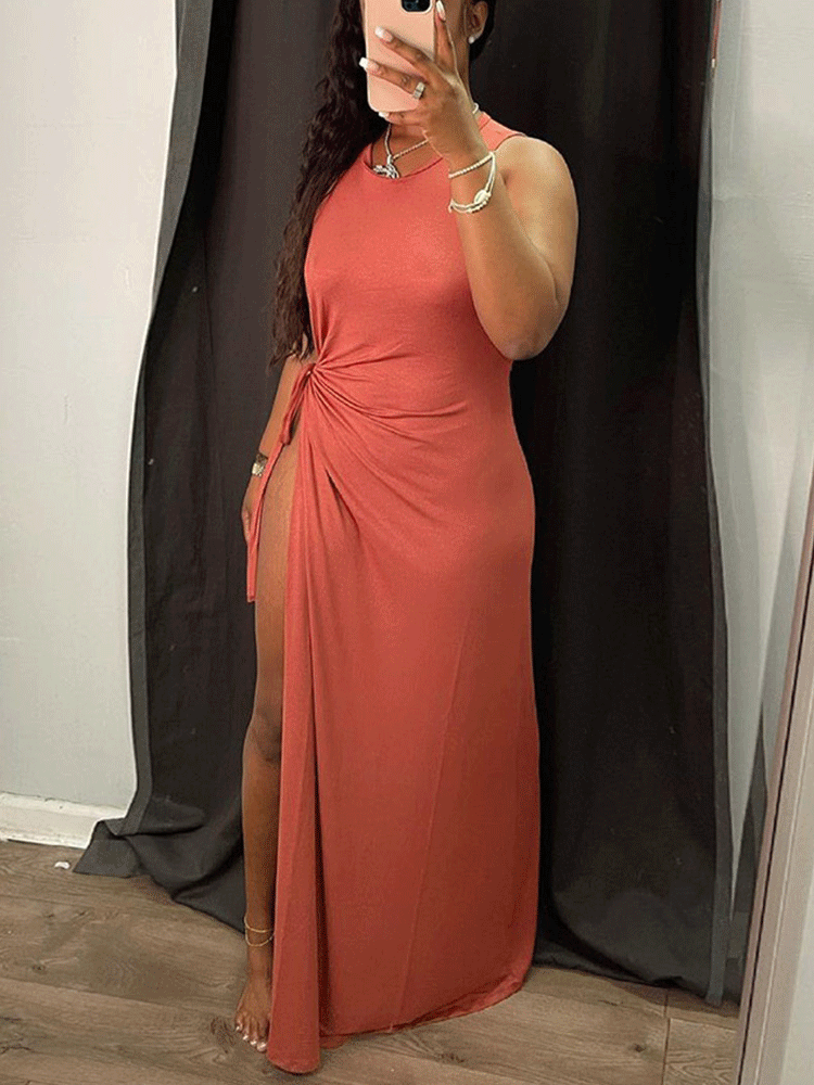 Woman wearing a rust-colored sleeveless maxi dress with a high slit, showing the full length of the dress.
