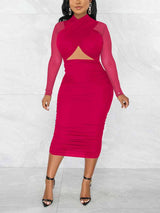 Woman wearing a magenta ruched sheath dress with a criss-cross neckline and sheer long sleeves.