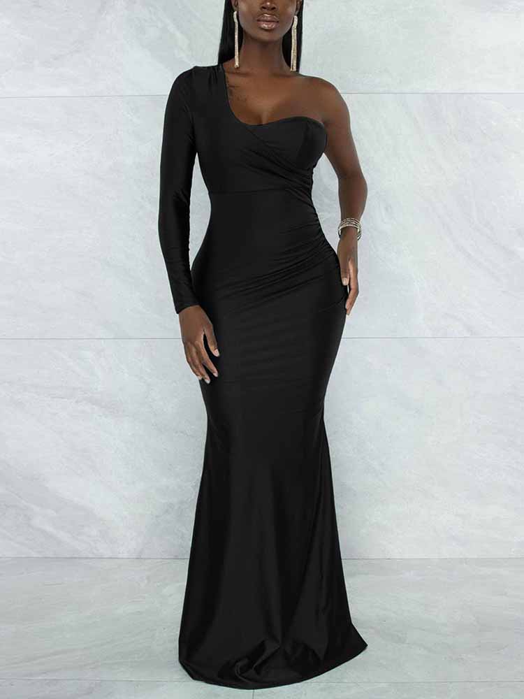 Woman wearing a floor-length, one-shoulder black dress with a long sleeve on the left side and a mermaid hem, standing against a marbled background.