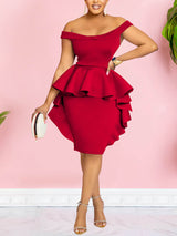 Front view of a woman wearing a red off-the-shoulder dress with ruffle details and an asymmetrical hemline, holding a clutch.