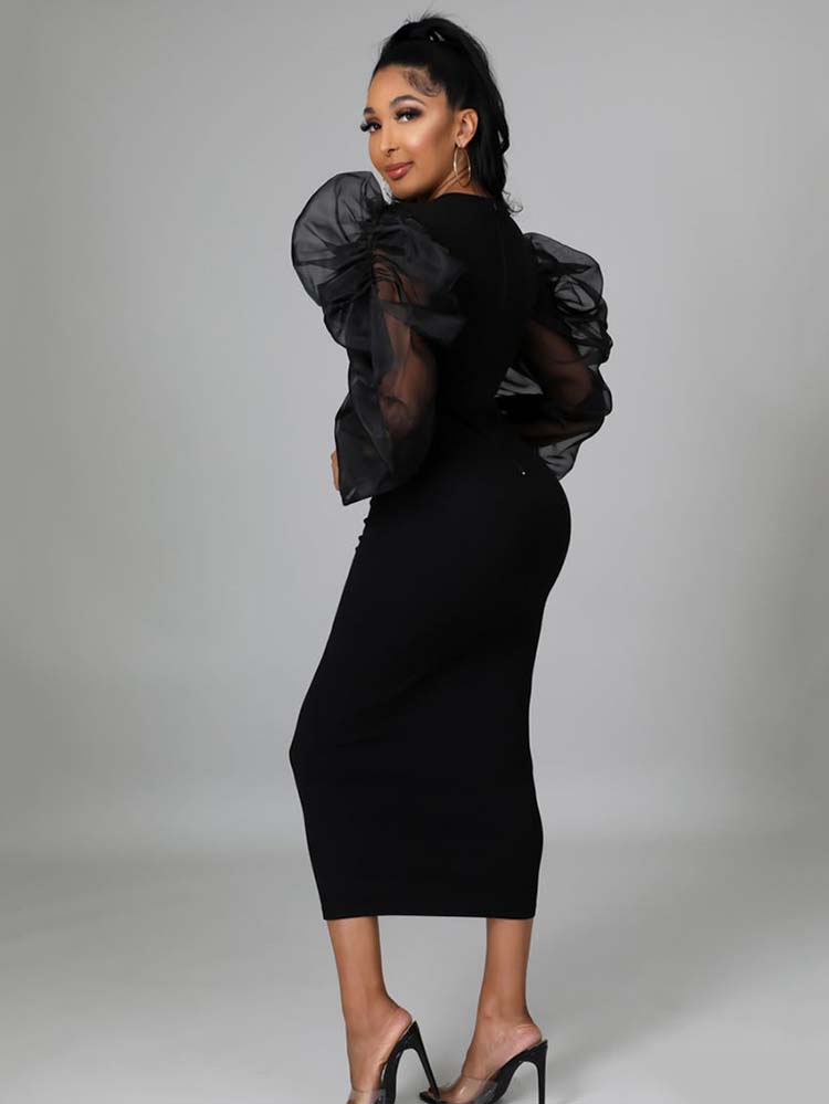 Back view of a woman in a black midi dress with sheer puff sleeves
