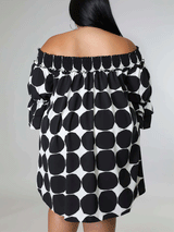 Rear view of a woman wearing a black and white polka dot off-the-shoulder dress.