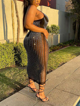profile view of a woman in a black embellished sheer midi dress and strappy heels