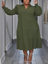 Plus-size model wearing a green tiered midi dress with voluminous sleeves and ruffled shoulders.
