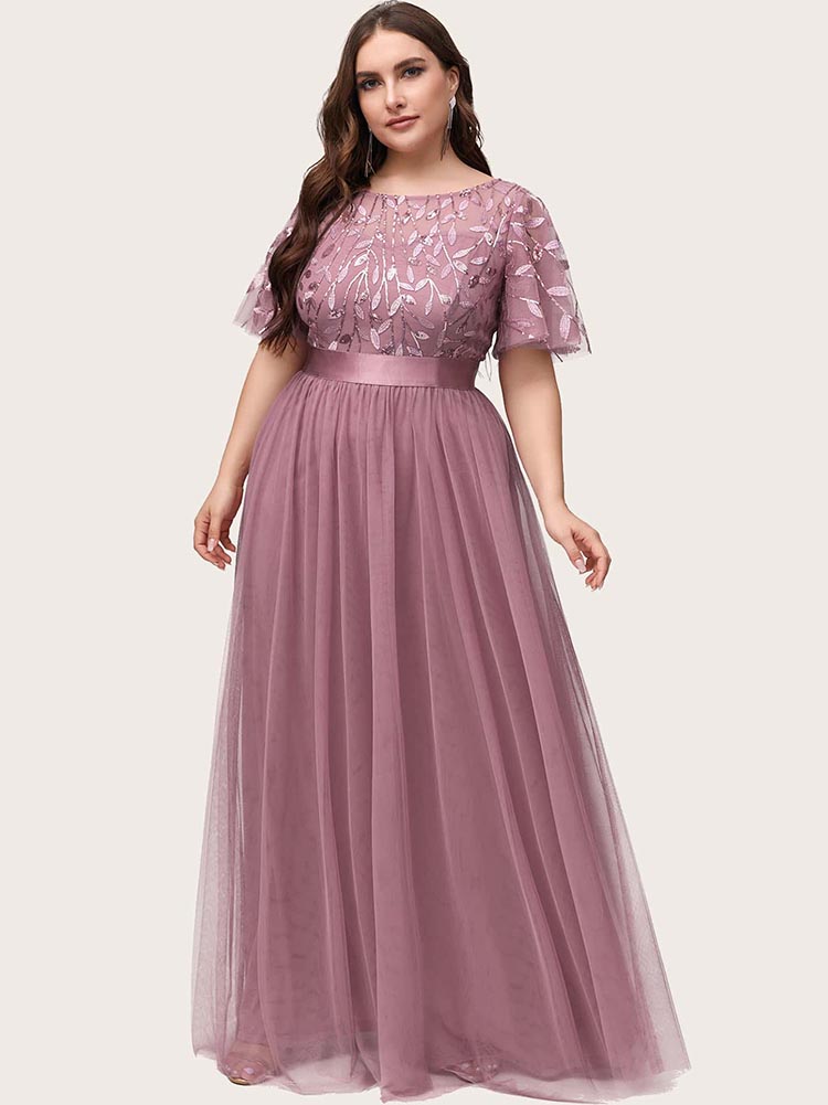 Full-length view of a woman in a dusty rose A-line maxi dress with embroidered flutter sleeves and a satin waistband.