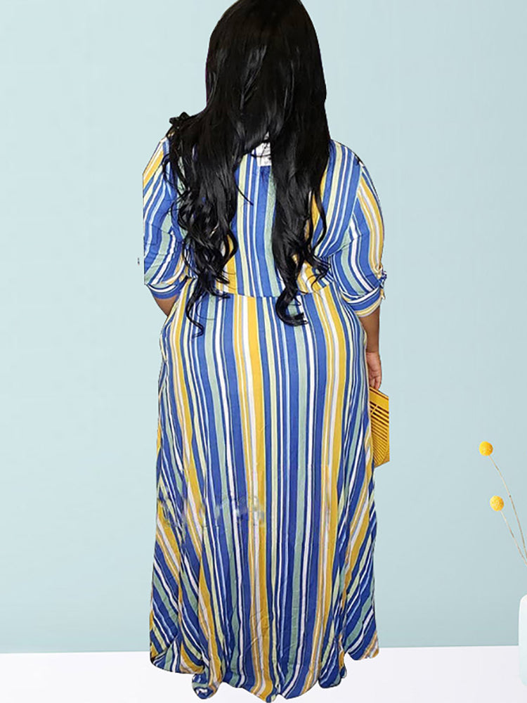 Back view of a woman wearing a blue, yellow, and white striped maxi dress with a belted waist.