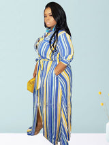 Woman wearing a blue, yellow, and white striped maxi dress with a belted waist and side slits, holding a yellow purse.