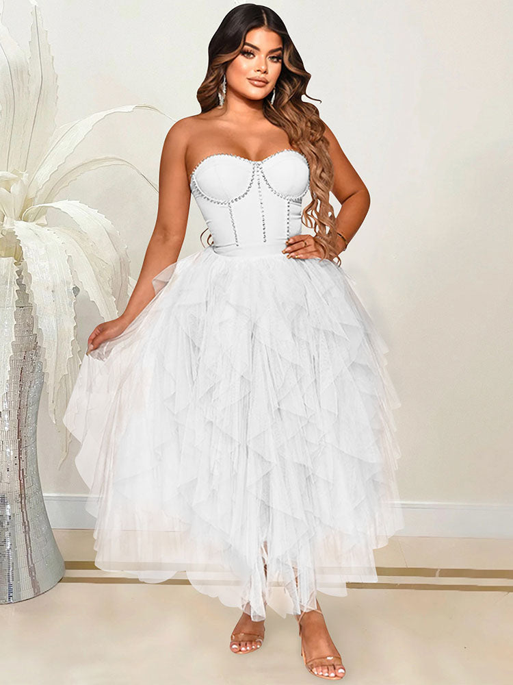 A woman in a white strapless dress with a beaded bodice and a tiered tulle skirt.