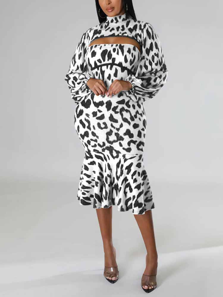 Woman wearing a black and white leopard print knit dress with a high neck, cut-out detail, long puff sleeves, and a mermaid hemline, posing with hands on hips.