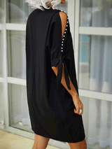 Back view of a woman in a black shift dress with a simple silhouette and cut-out sleeves.