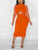 Woman wearing an orange ruched sheath dress with a criss-cross neckline and sheer long sleeves.