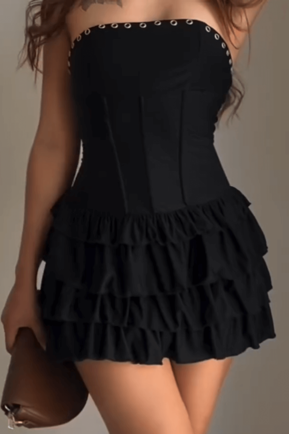 Detail shot of the upper part of a black strapless mini dress with a ruffled skirt and corset bodice.