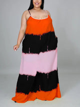 Woman wearing an orange, black, and pink tie-dye maxi dress with spaghetti straps and pockets, front view.