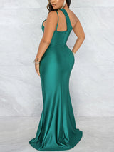Woman in a floor-length emerald green satin gown with an asymmetrical neckline, showing the back view.