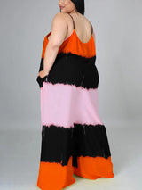 Woman wearing an orange, black, and pink tie-dye maxi dress with spaghetti straps and pockets, back view.