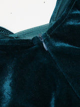 Side view of a woman in a long, teal velvet dress with sequined skirt and bishop sleeves.