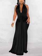 Woman wearing a long black halter neck dress with a deep V-neck and ruched waist