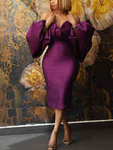 Woman wearing a purple off-the-shoulder satin midi dress with voluminous bishop sleeves and a V-neckline.
