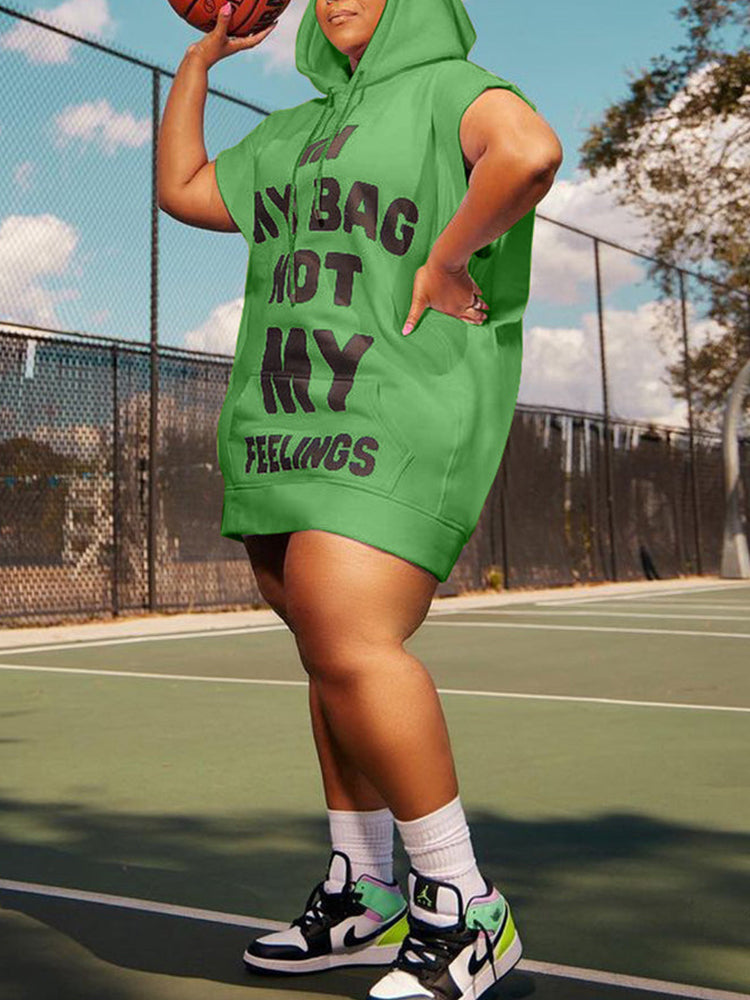 Plus-size woman wearing a green hooded mini dress with a graphic print, paired with white socks and sneakers, posing on a tennis court with a basketball.