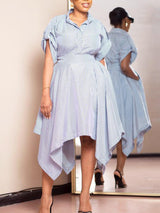 Woman wearing a blue and white striped shirt dress with an asymmetrical hemline and puffed sleeves.