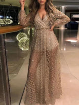 Woman in a long, sheer, sparkling gold dress with long sleeves and a V-neck, posing indoors.