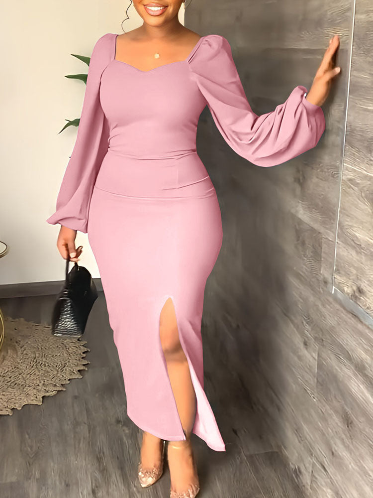 A woman in a pink dress with voluminous sleeves and a front slit, leaning against a wall.