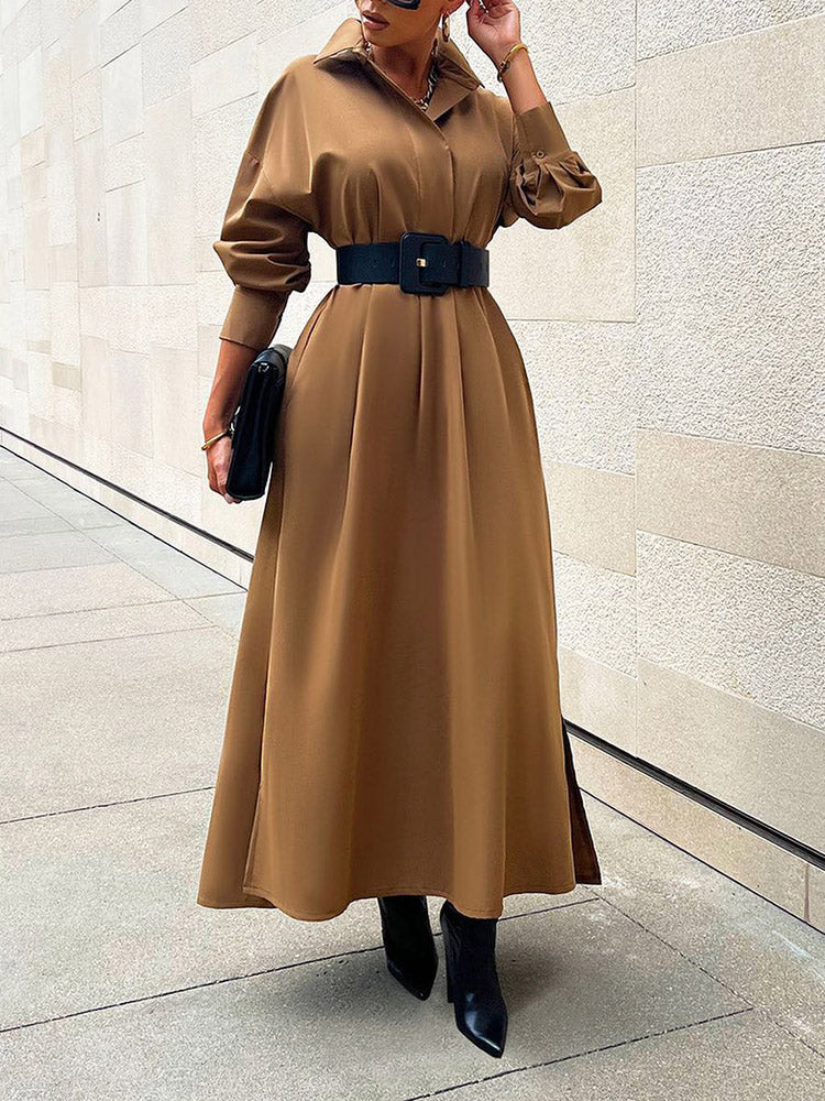 Woman wearing a long brown collared dress with a wide black belt and black boots.