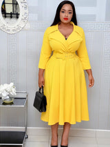 Woman in a yellow fit and flare dress with a belted waist and lapel collar.