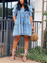 woman wearing a blue denim tiered babydoll dress with puff sleeves and a square neckline
