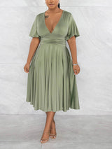 Woman wearing a light green midi dress with a V-neck and flutter sleeves