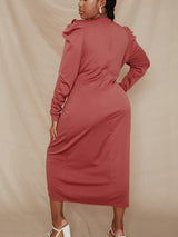 Back view of a plus-size woman wearing a rust-colored long-sleeved V-neck ruched wrap dress with puff sleeves against a beige backdrop.